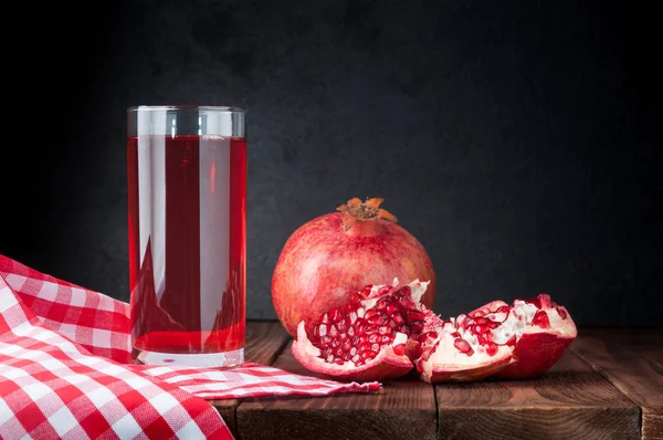 Pomegranate and pomegranate juice on a wooden background. Pomegranate seeds on table. Beautiful ripe pomegranate.