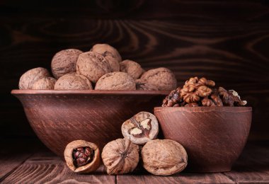 Ceviz eski rustik masa. Ceviz taneleri bir tencerede. Kahverengi bir tencerede bütün ceviz badem. Güzel ceviz ve ceviz parçaları.