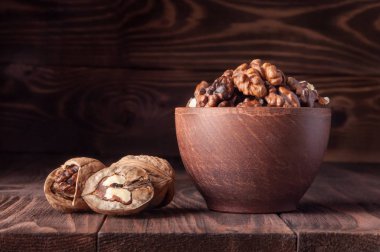 Ceviz eski rustik masada. Bir tencerede bir ceviz taneleri. Bütün ceviz taneleri. Güzel ceviz ve ceviz parçaları.