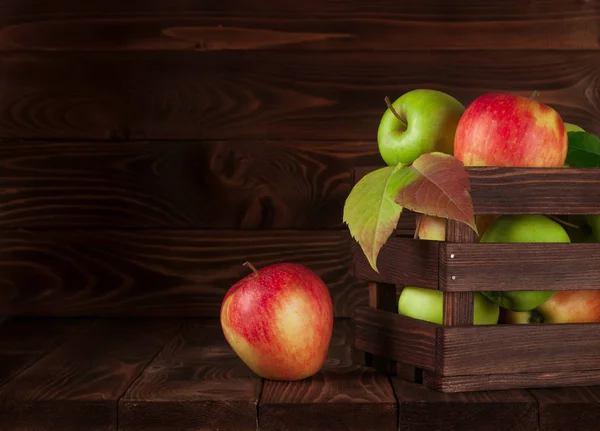 Apples in a wooden rustic box on old rustic wooden table. Red apples, green apples. Delicious apple. Apples on table.