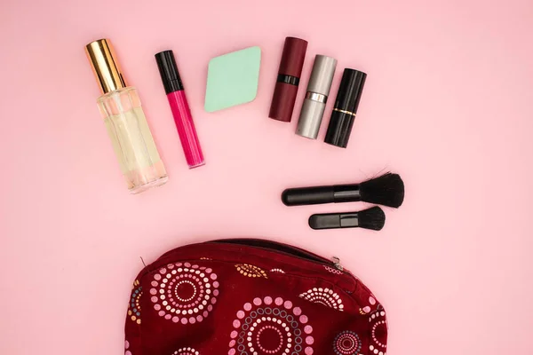 Vanity case with beauty products and cosmetics for woman on pink background