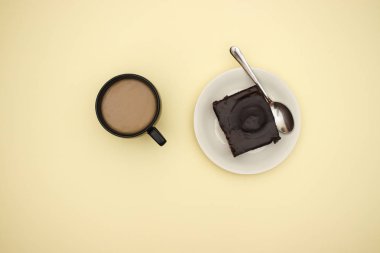Sarı arka planda çikolata kek ve fincan kahve 