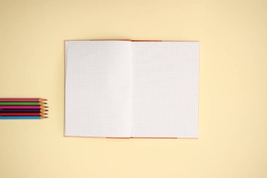 Sarı arka planda açık Notebook ve renk kalemler 