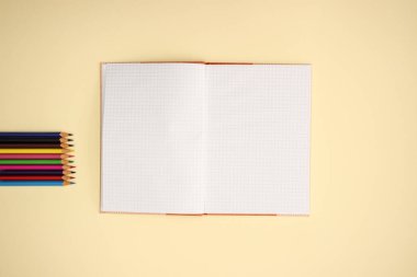Sarı arka planda açık Notebook ve renk kalemler 