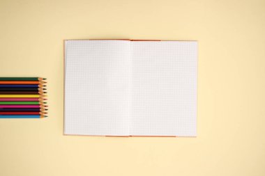 Sarı arka planda açık Notebook ve renk kalemler 