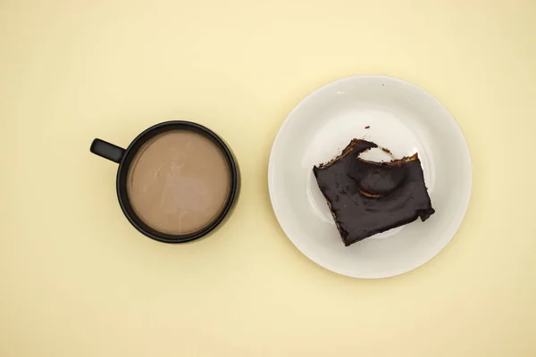 Cup of coffee and chocolate cake on yellow background