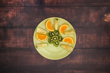 Ahşap masada taze meyve salatası ile yeşil plaka 