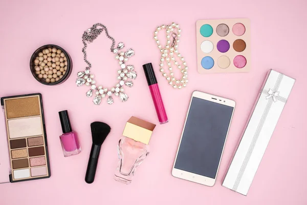Woman\'s accessories and make up on pink background