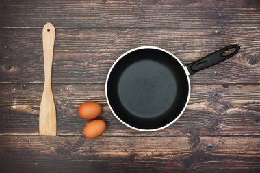 Masa ve yumurta ve ahşap kaşık üzerinde boş Pan