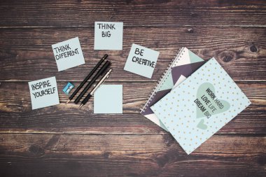 Ahşap masada motivasyon notları, defter ve kalemler 