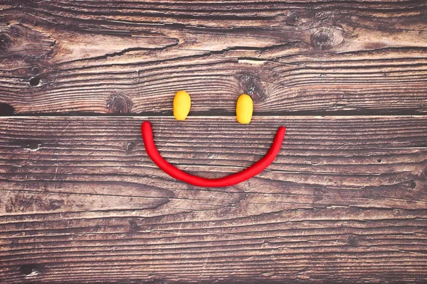 Smiley made of play dough on wooden background