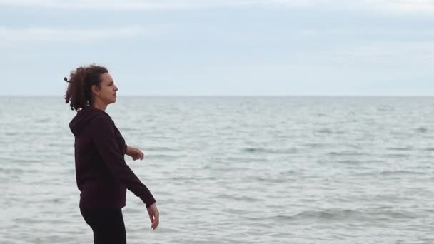 Молодая Женщина Бросает Камень Вдалеке Пляже Холодный День — стоковое видео
