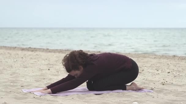 美しく若い女性はビーチでヨガを練習します 健康的なライフスタイル ビーチでレクリエーションをしている若い女性 — ストック動画