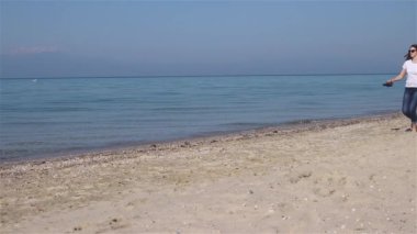 Sahilde yalınayak koşan mutlu genç kadın ve elinde ayakkabı almak. Özgür ve mutlu hissedin
