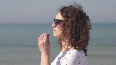 Genç ve güzel bir kadının yakın çekim plajda müzik dinlemek için kulaklık koymak