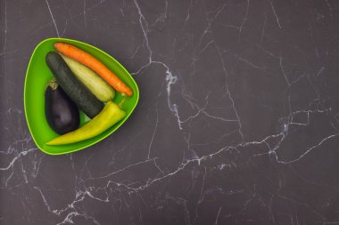 Mutfak masasında yeşil tencerede taze ve organik sebzeler 