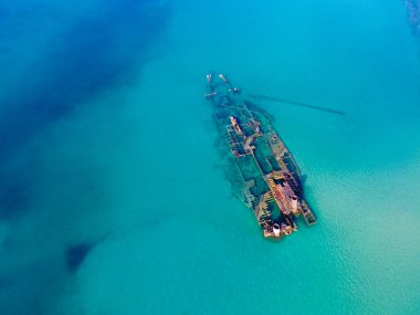 Mavi açık denizde eski bir gemi enkazı. Denizde mahsur kalan terk edilmiş geminin havadan görüntüsü. 