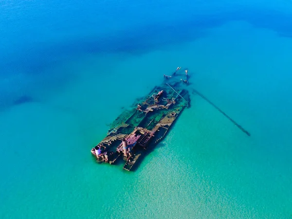 Old shipwreck in blue clear sea. Aerial view of abandoned ship stranded ship in sea