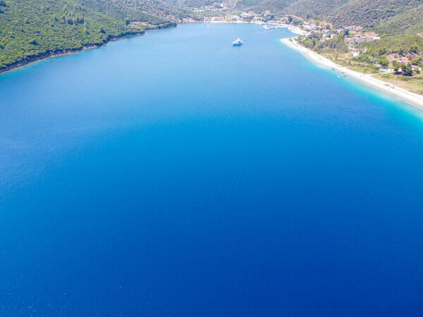 Шикарная яхта, плывущая по синему морю, окруженному берегом 