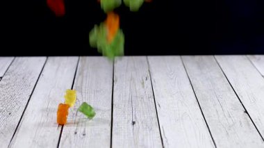 Tahta masaya düşen jelibon ayıcıkları. Yavaş çekim 