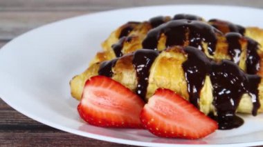 Beyaz tabakta dilimlenmiş çilekli lezzetli tatlı kruvasanlar. Kapat. 