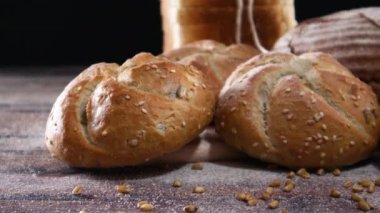 Fırın ürünleri, organik çavdar ekmeği, çörekler, ahşap masa üzerinde simit ve siyah tema