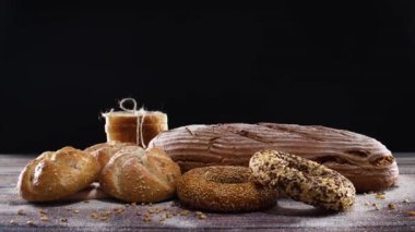 Fırın ürünleri, organik çavdar ekmeği, çörekler, ahşap masa üzerinde simit ve siyah tema