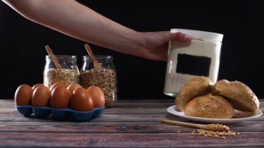 El, masaya beyaz un ve tam buğday unu koy. Çörek, yumurta ve yulaf ezmesini kavanoza koy.