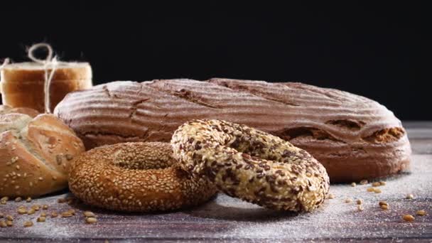 Bageriprodukter Ekologiskt Rågbröd Bullar Bagels Träbord Och Svart Tema — Stockvideo