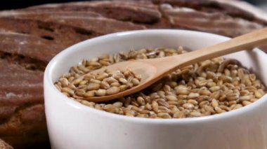 Beyaz kasedeki organik tahılları ahşap kaşık ve masanda pişirme malzemeleriyle kapatın.