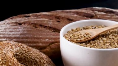 Beyaz kasedeki organik tahılları ahşap kaşık ve masanda pişirme malzemeleriyle kapatın.