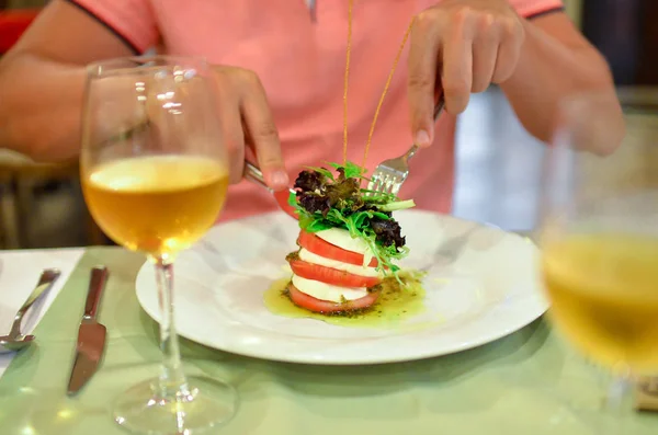 Taze fesleğen, mozzarella ve domates ile İtalyan geleneksel salata Caprese yeme için hazır çatal ve bıçak ile erkek eller