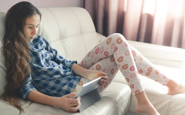 Tablet pc ile evde oturan genç kız. Güzel beyaz uzun saçlı kız yaşam tarzı görüntü.