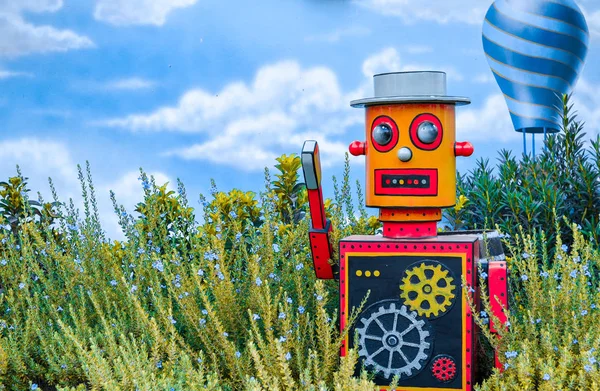 Mavi Ballon ve arkasında gökyüzü ile yeşil çiçek arka plan üzerinde çok renkli parlak ahşap oyuncak robot