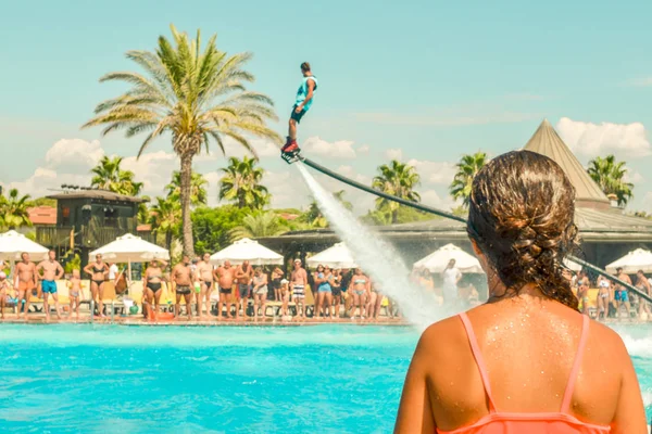 Havuzda sinek Board watershow izlerken genç kız. Arkadan görünüm.