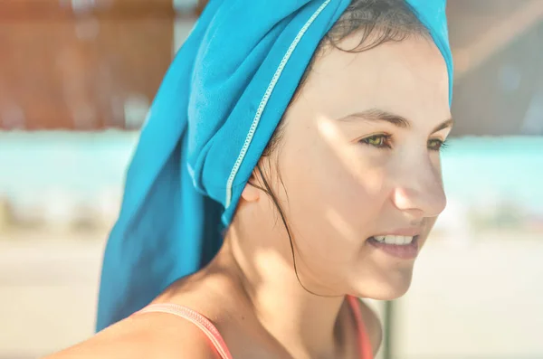Sahilde yeşil gözlü, kafasında mavi havluyla gülümseyen genç kızın yakın plan yaşam tarzı portresi. Yaz, yaz neşesi, tatil, tatil