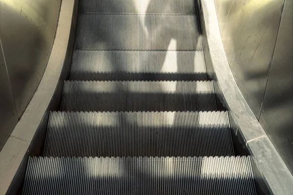 Sombras de duas pessoas em uma escada rolante — Fotografia de Stock