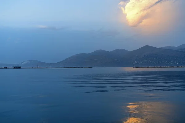 Ocean landscape with an orange glowing cloud above a mountain range — Stock Photo, Image