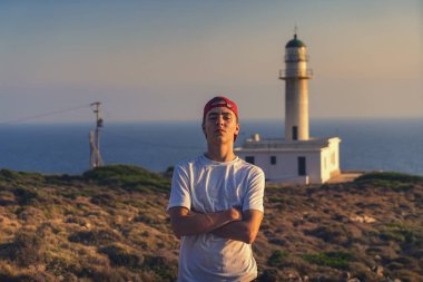 Yunanistan'da bir deniz feneri önünde genç bir adamın portresi