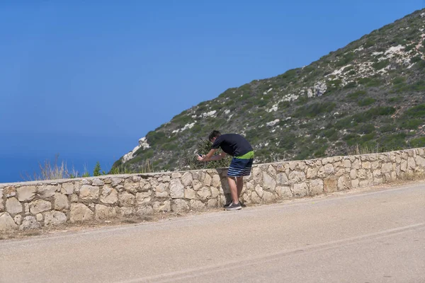 Junger Mann fotografiert mit Handy in mediterraner Landschaft — Stockfoto