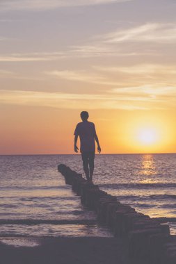 baltık denizi üzerinde gün batımı, genç adam bir kasık üzerinde dengeleme