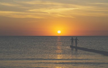 baltık denizi üzerinde gün batımı, iki genç bir kasık üzerinde dengeleme vardır