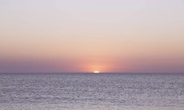 日落在海洋的地平线上，无云的天空 — 图库照片