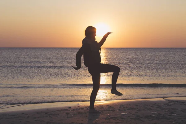 Sonnenuntergang über dem Meer, Frau tanzt am Strand — Stockfoto