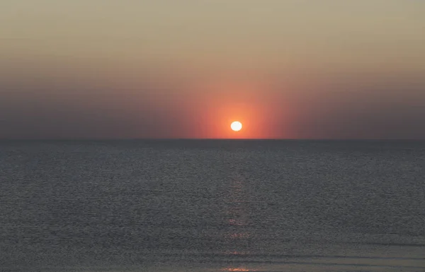 Puesta de sol sobre el horizonte del océano con cielo despejado — Foto de Stock