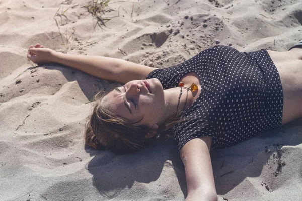 Junge Frau liegt mit geschlossenen Augen am Strand — Stockfoto