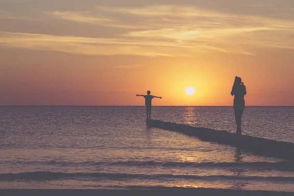 Sonnenuntergang über der Ostsee, zwei Teenager balancieren auf einer Leiste — Stockfoto