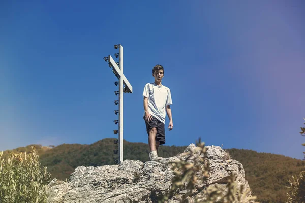 Italy Tuscany, young man is standing next to a summit cross — Stock Photo, Image
