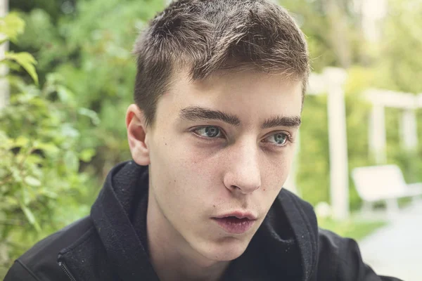 Portrait d'un jeune homme drôle assis dans un parc — Photo