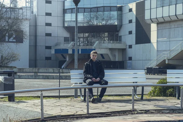 Portrait of a sad young man sitting on a bench — Stock Photo, Image